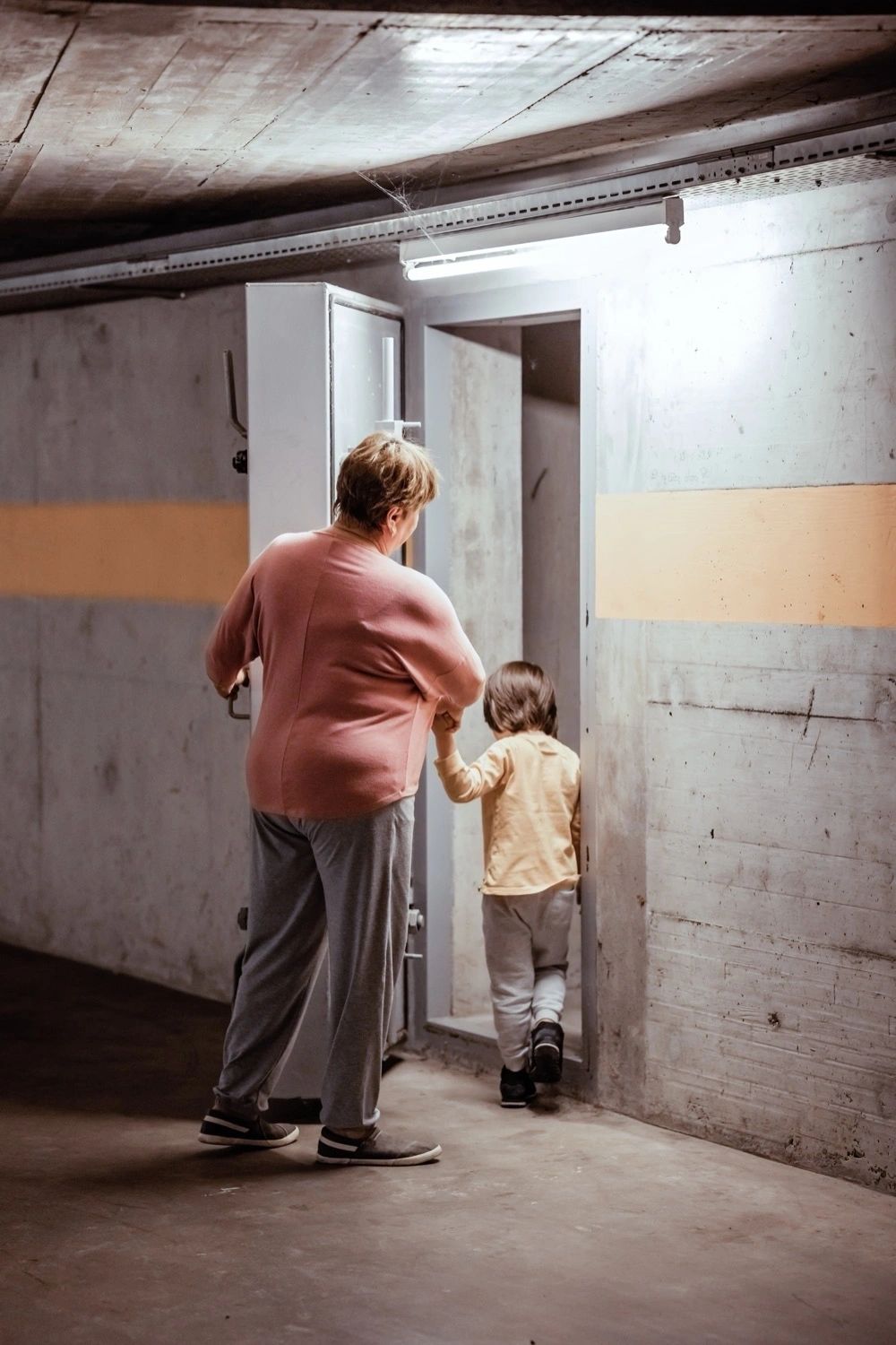 An adult and child enter a concrete shelter. Illustrative stock photograph, not the Grums exercise. Kiwitanya / Envato.
